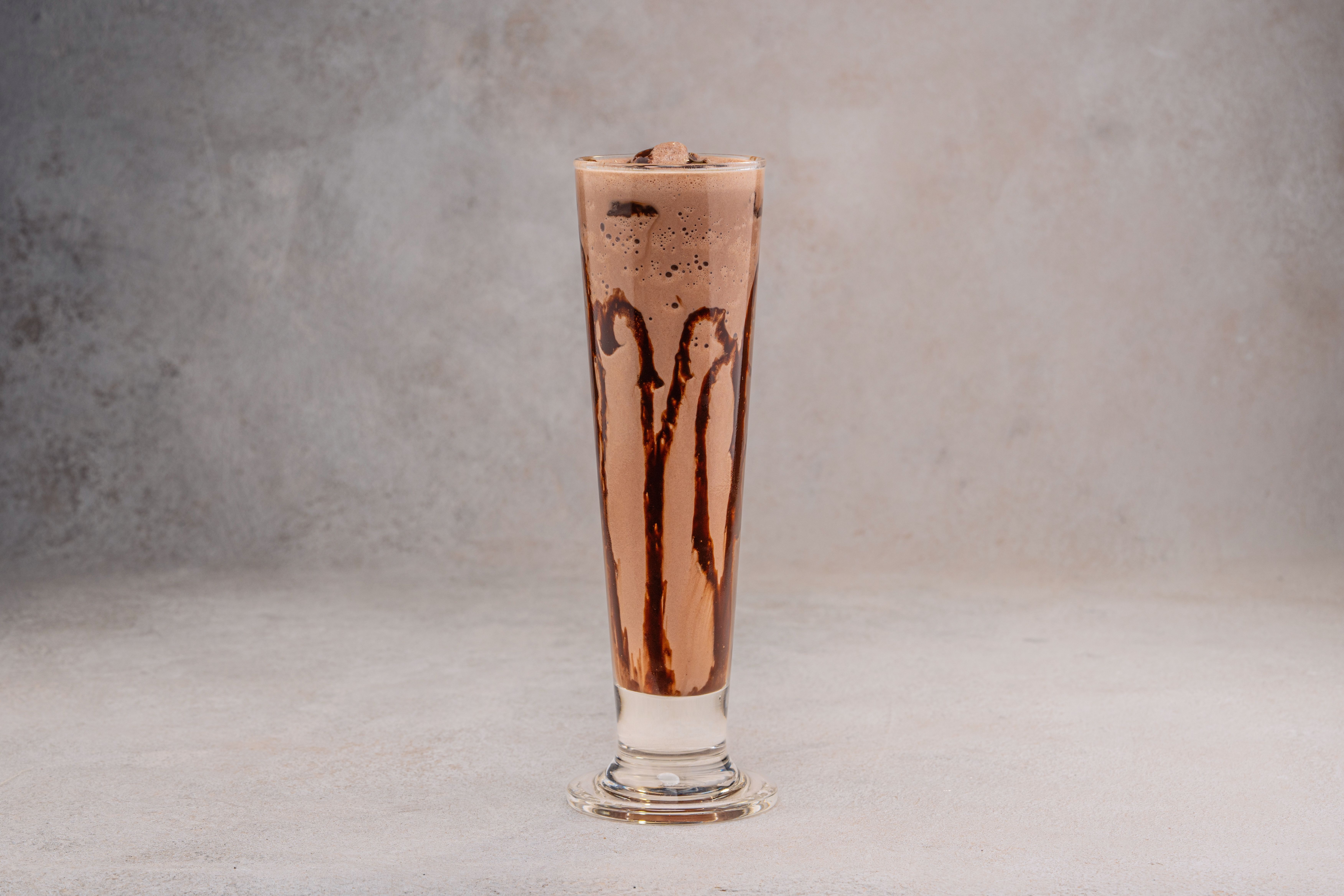 Chocolate milkshake in glass with whipped cream and straw