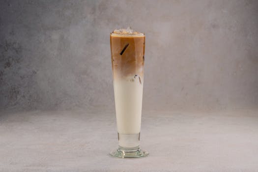 A refreshing iced coffee latte in a tall glass on a neutral gray background.