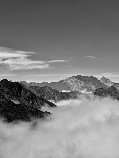 Free Captivating aerial view of rugged mountains shrouded in clouds, captured in monochrome. Stock Photo