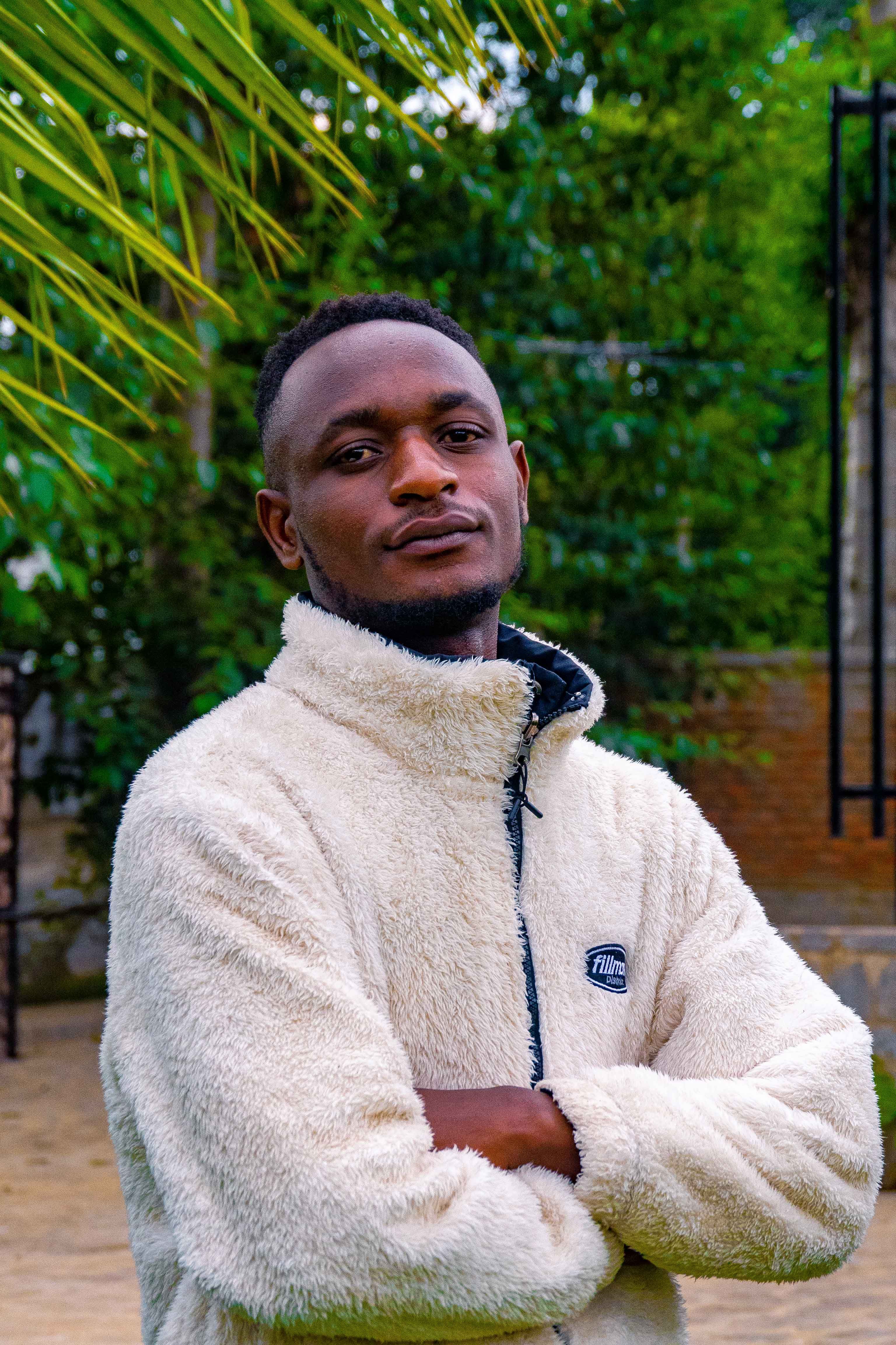 Confident young man with arms crossed in an outdoor setting. Fashion portrait.