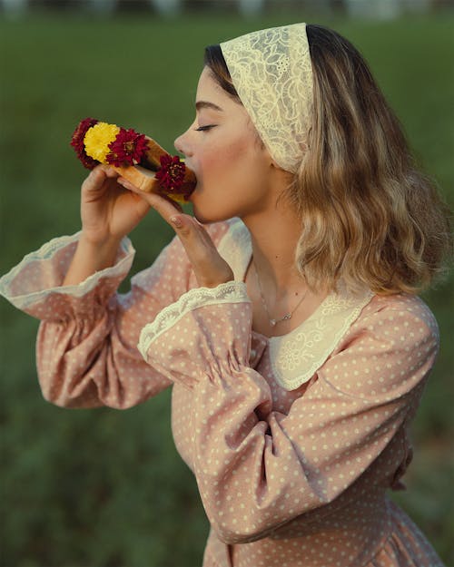 Woman Eating Bread with Flowers on a Meadow