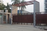 A large automated iron gate as the entrance to a modern urban building, surrounded by palm trees.