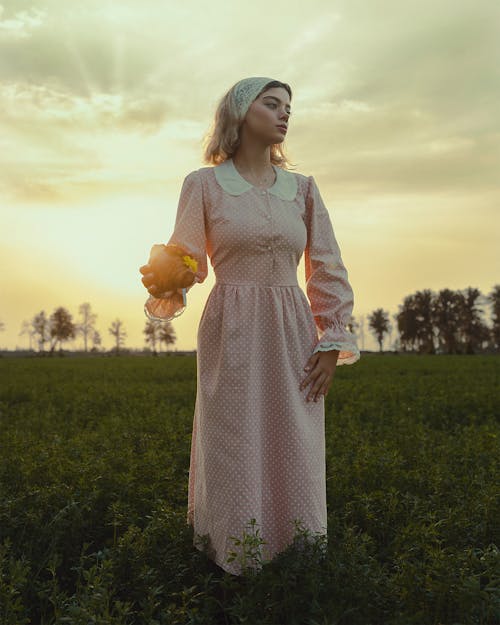 Woman in Pink Sundress on Field at Sunset