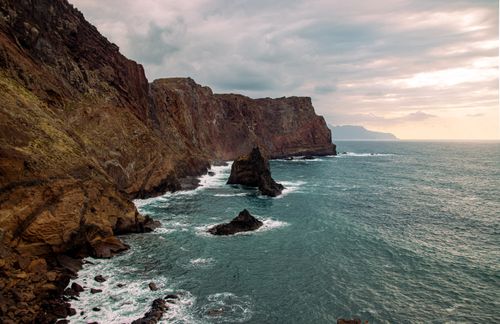 Free Breathtaking view of rocky cliffs meeting the ocean under a cloudy sky, perfect for adventure and nature themes. Stock Photo