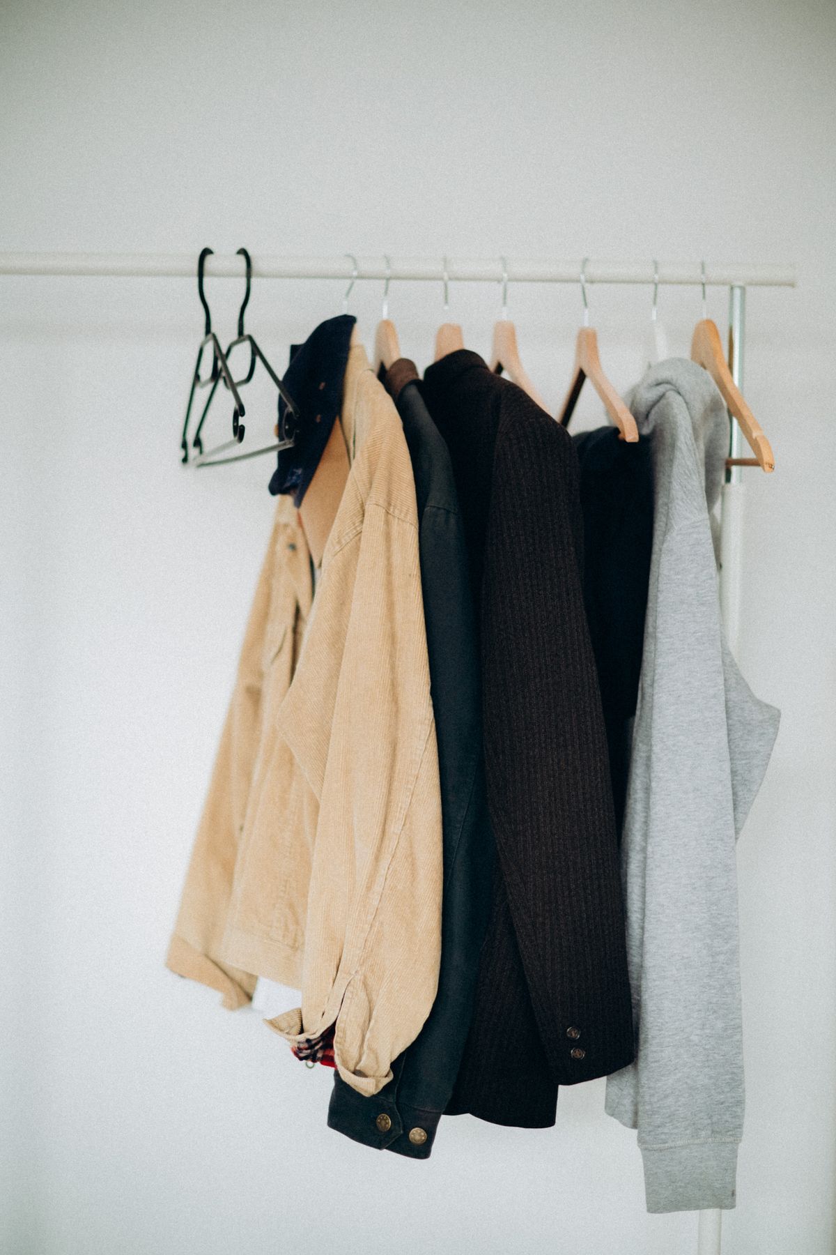 Outerwear hung on wooden hangers against a plain wall