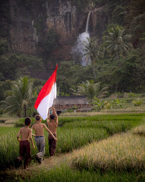 Boys Walking with Flag of Indonesia on Field