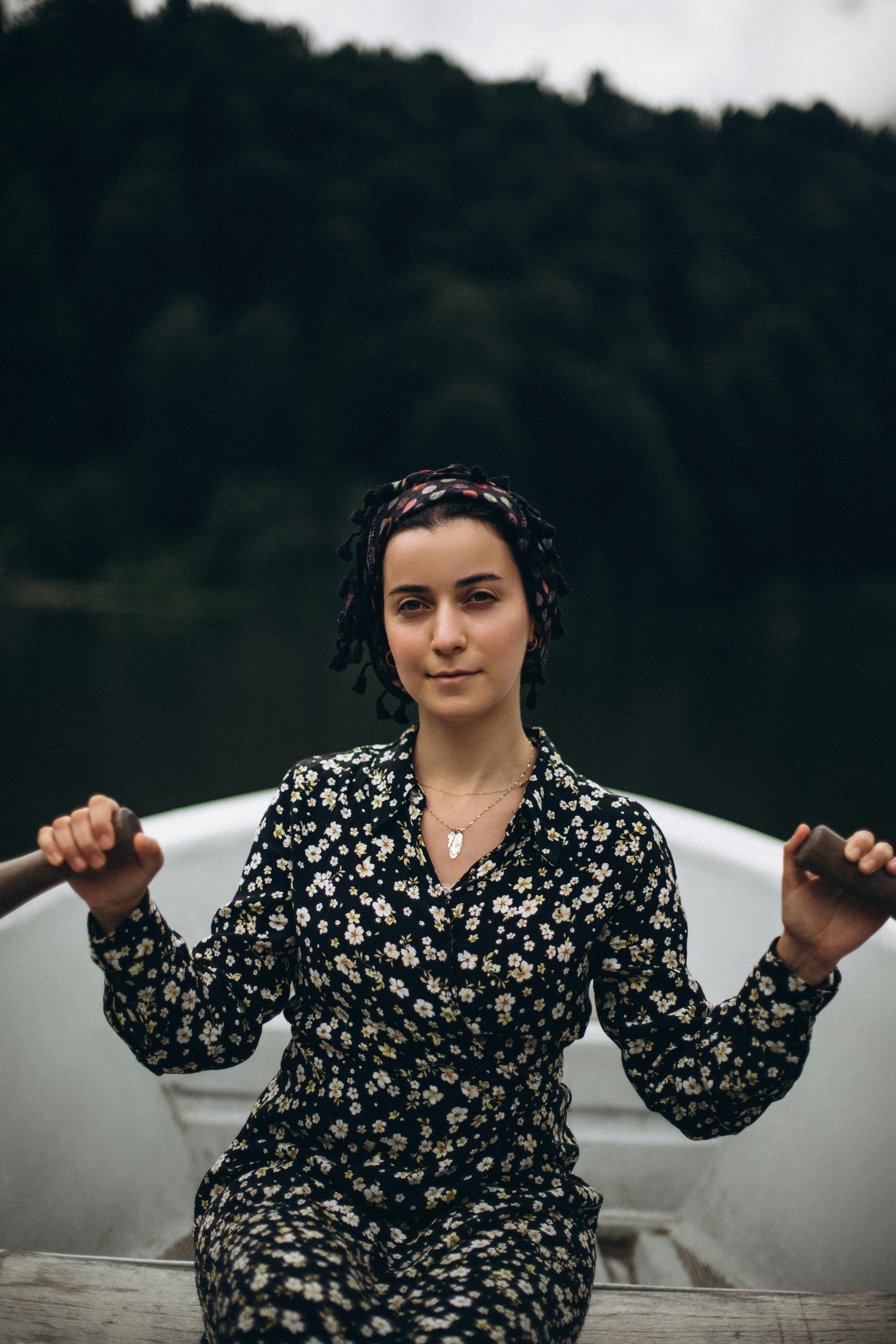 a woman in a floral dress sits in a boat