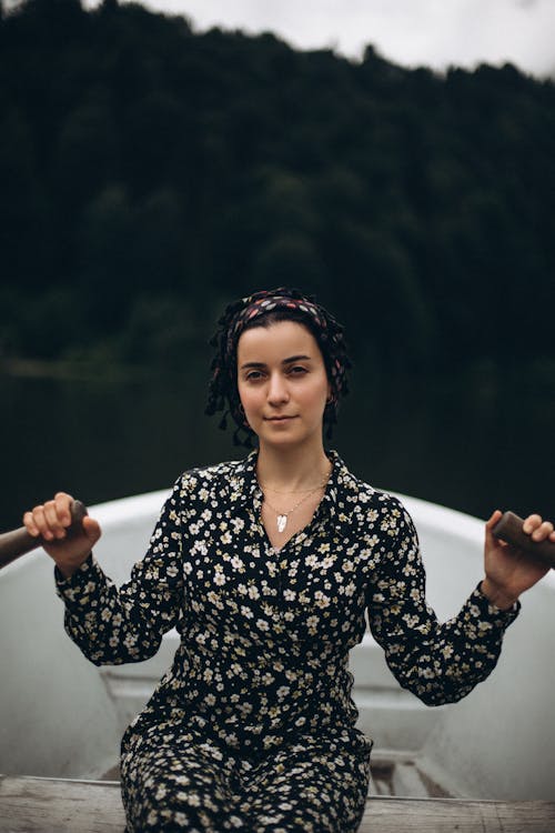 A woman in a floral dress sits in a boat