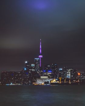 Stunning nighttime view of Toronto skyline with CN Tower reflected on the waterfront.