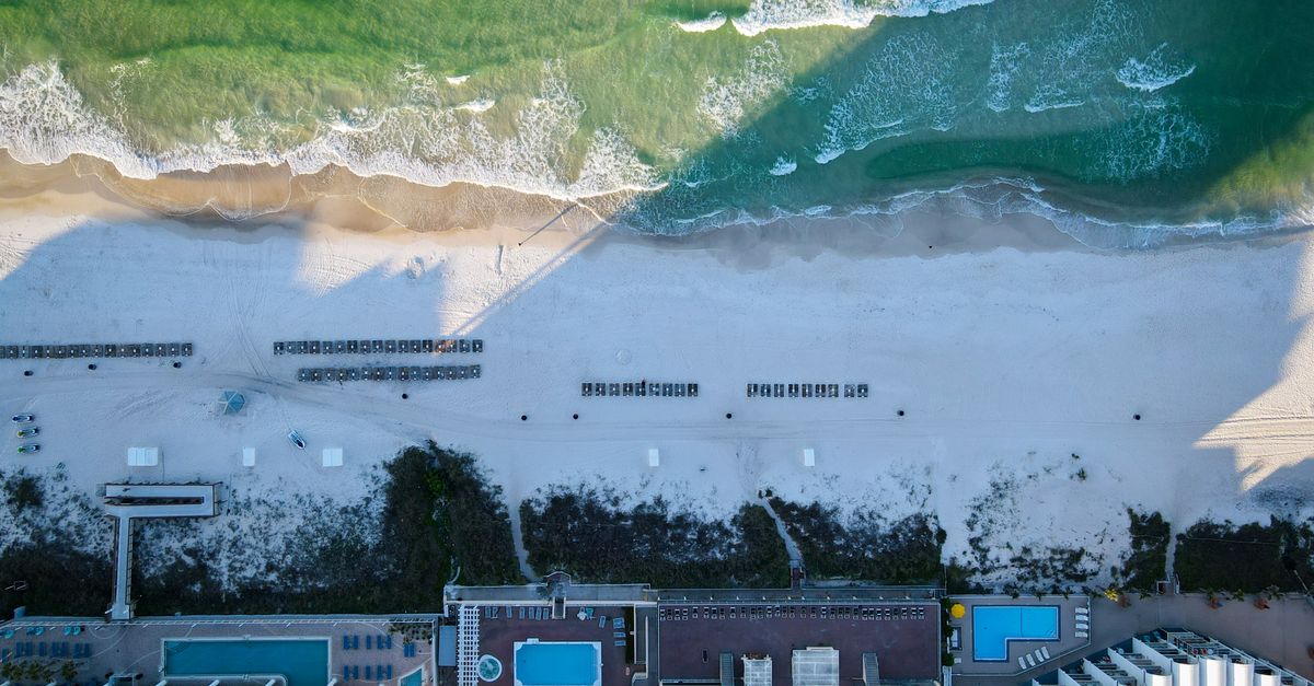 Stunning aerial shot of a beachfront resort in Panama City Beach, FL with pools and coastline.