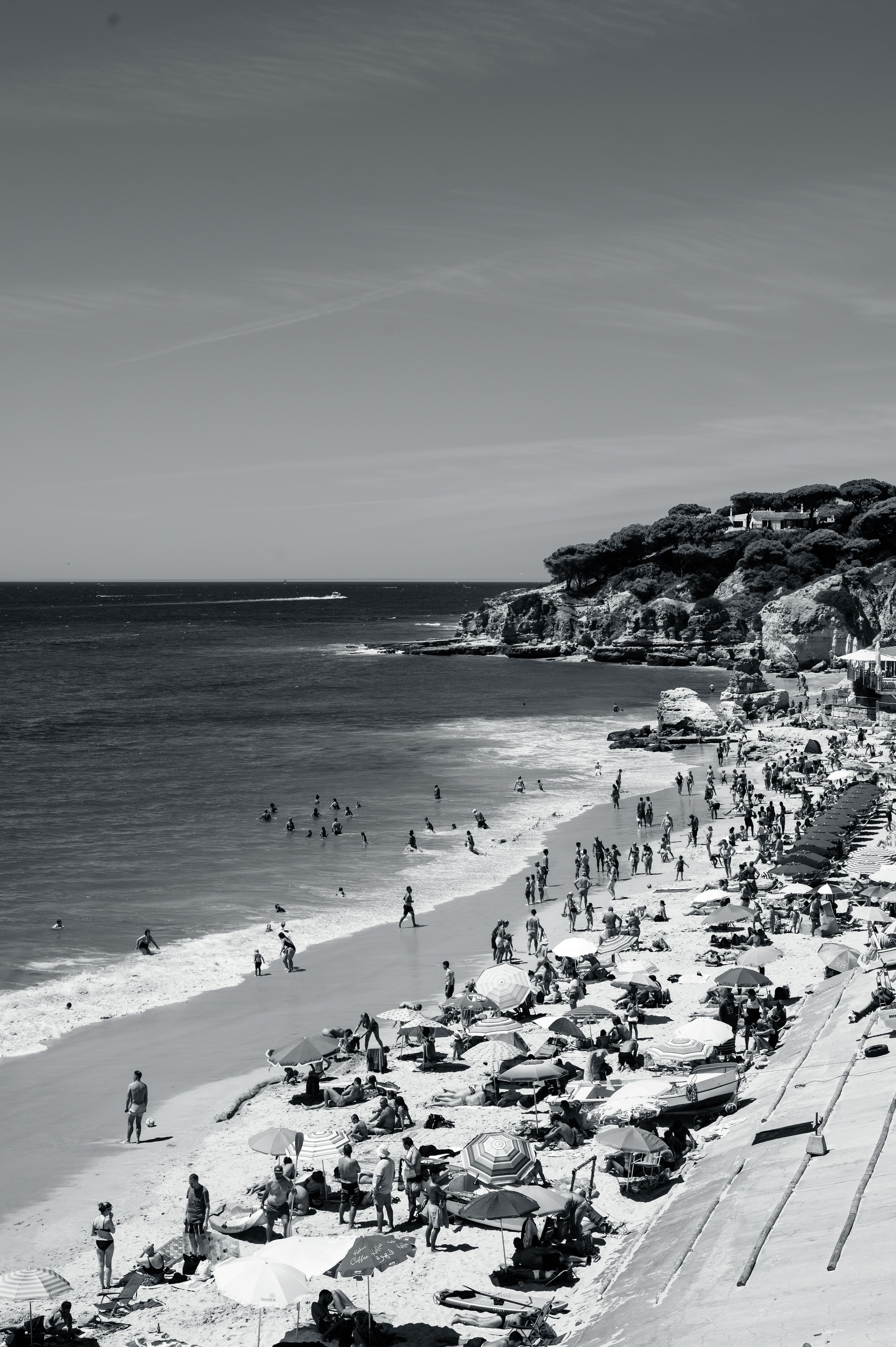 Aerial view of a crowded Albufeira beach with sunbathers and umbrellas during summer.