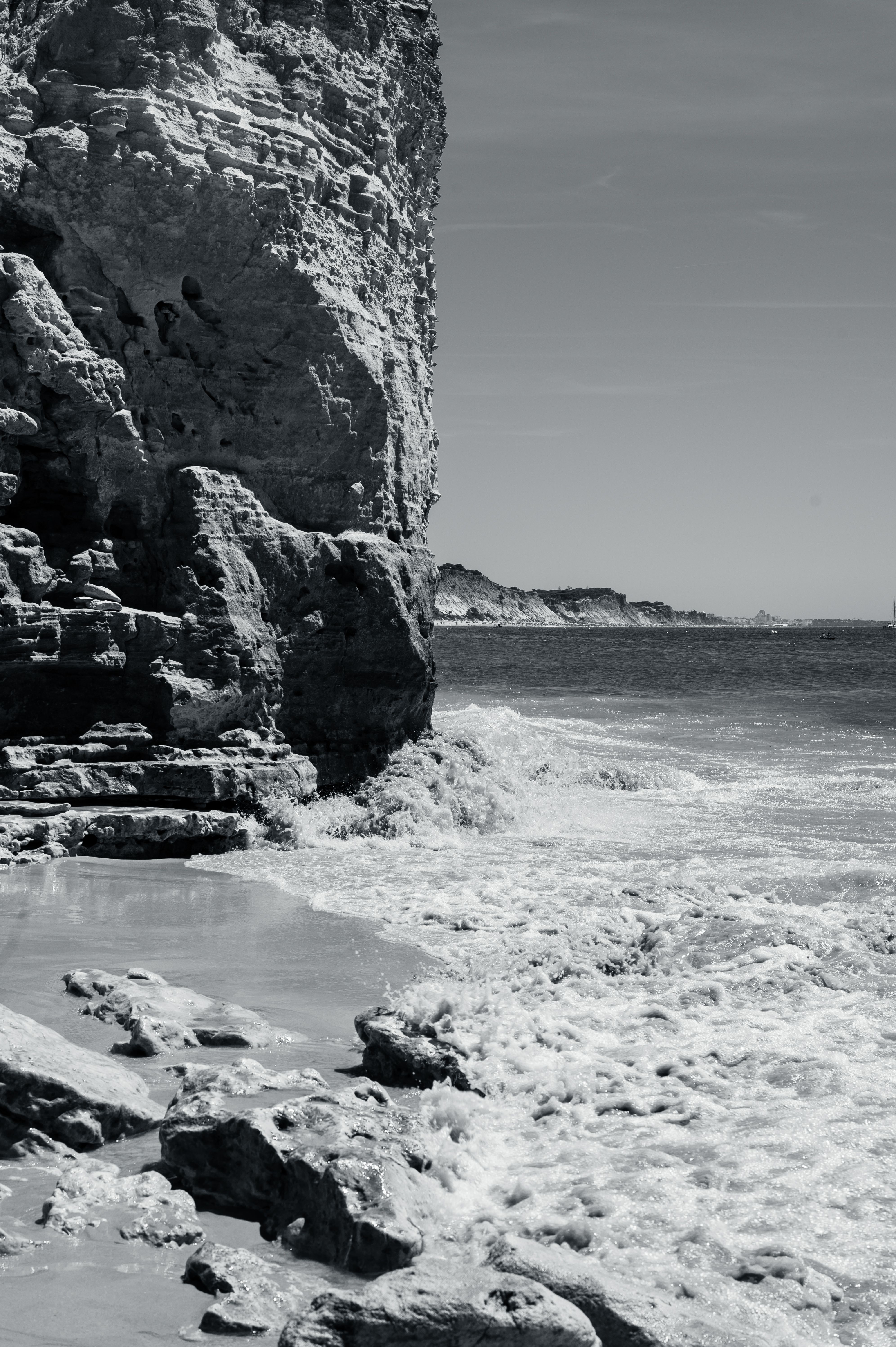 Black and White Photo of a Rocky Cliff and Waves Washing Up the Beach ...