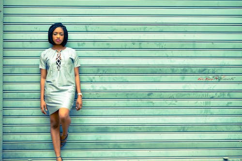 Woman in White T-shirt and Black Shorts Standing Beside Green Wall