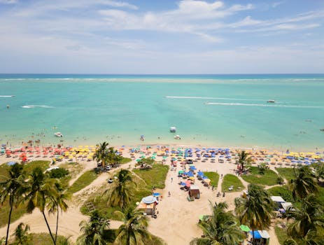 A vibrant aerial view of a tropical beach in Antunes, Brazil, with colorful umbrellas and turquoise waters.