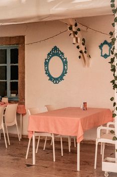 Cozy Mediterranean café setup with pink tablecloths, white chairs, and blue decorative accents.