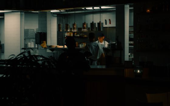 Chefs working in a dimly lit urban kitchen, showcasing the night ambiance.