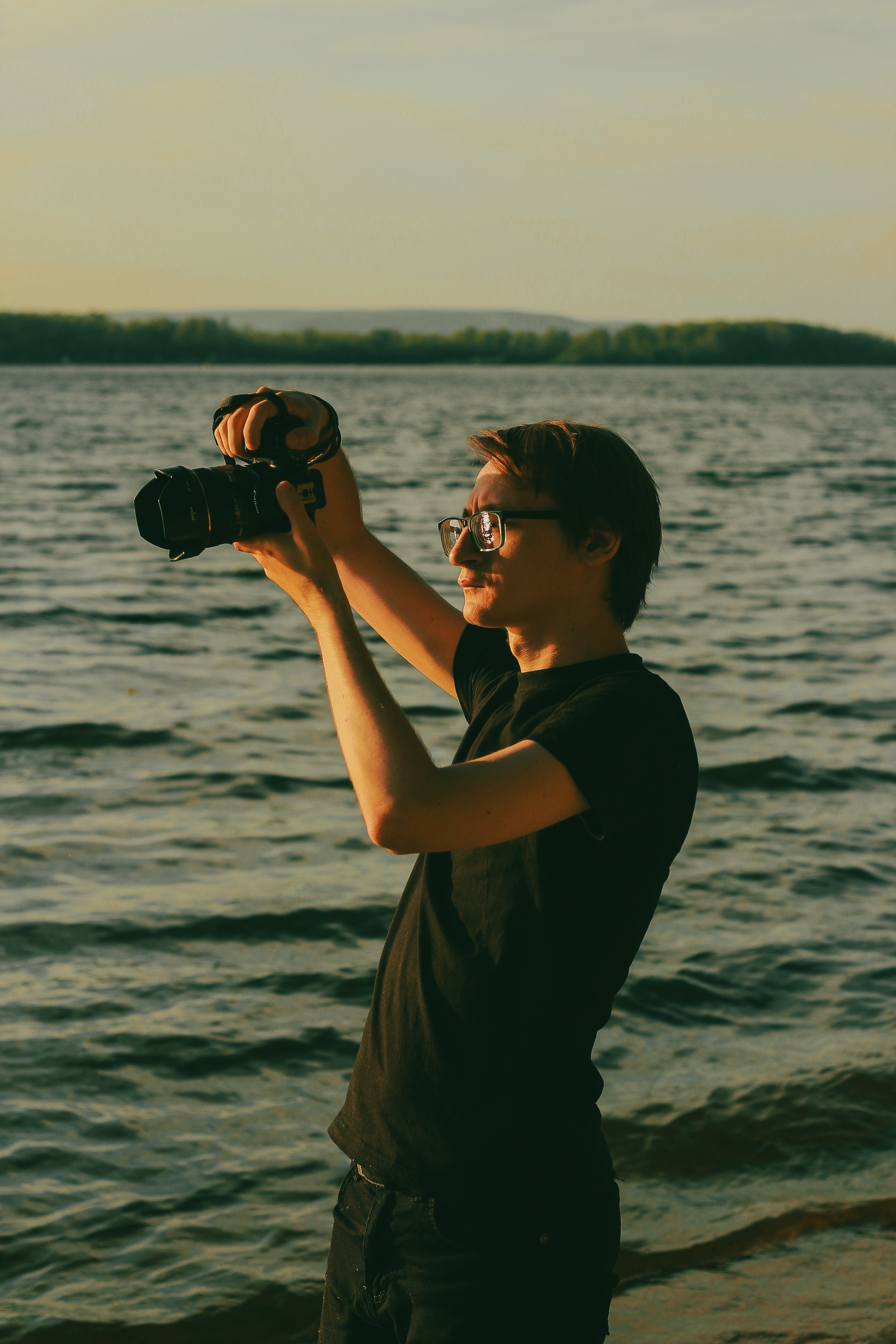 A young man capturing moments on a beach in Samara, Russia at sunset with a professional camera.