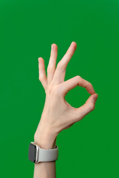 Close-up of a Hand Showing OK Sign on Green Background