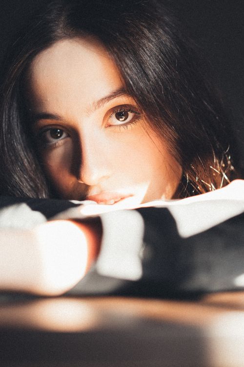 Free Close-up portrait of a woman with long dark hair and captivating eyes, bathed in natural light. Stock Photo
