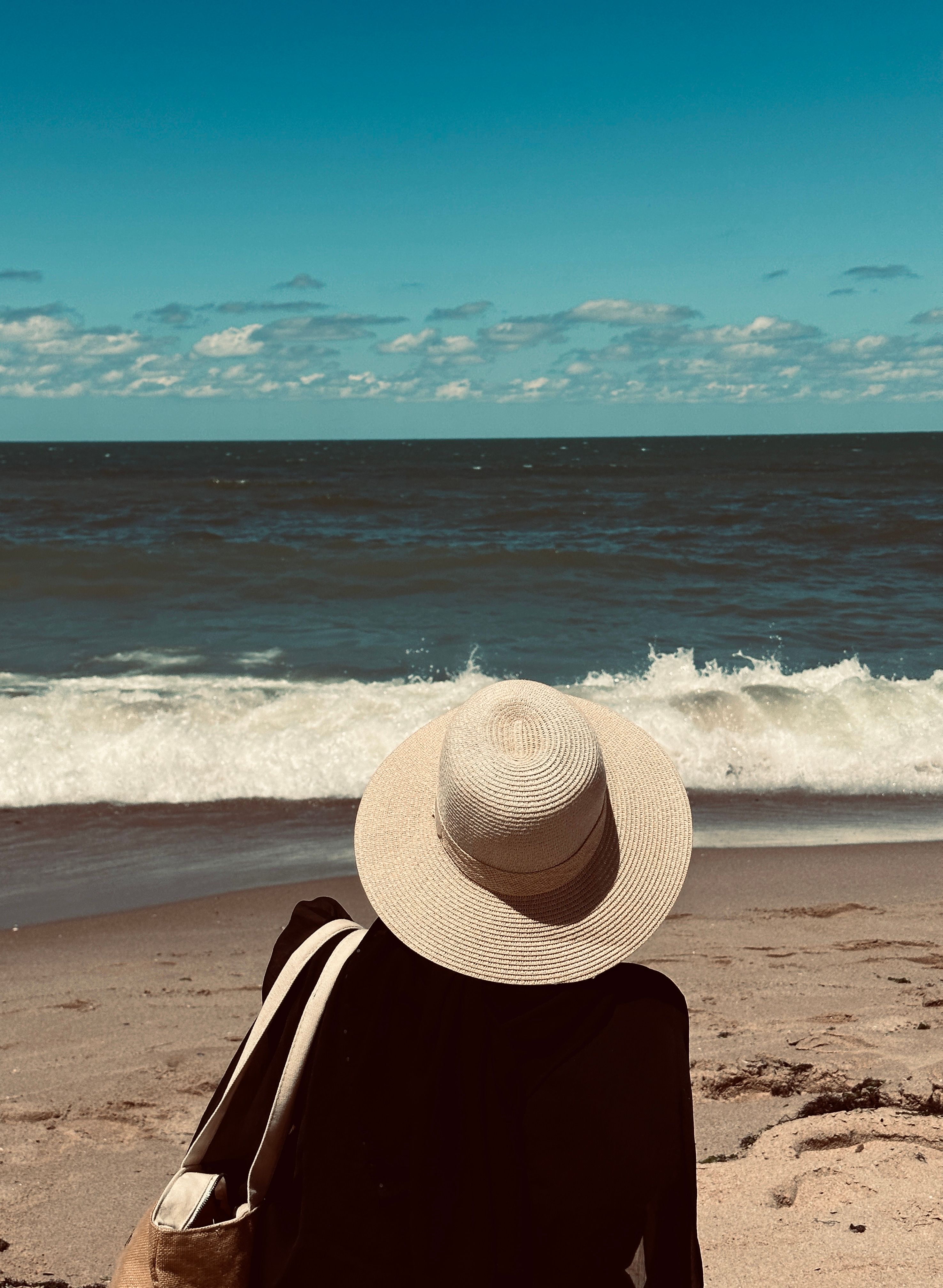 Woman in Black Shirt and Straw Hat Sitting on a Beach · Free Stock Photo