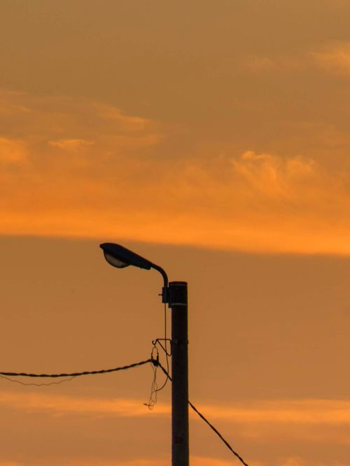 Free Silhouette of a street lamp with electric wires against a dramatic orange sky at sunset. Stock Photo