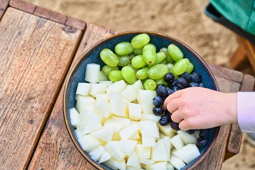 Close-up of a Child Taking Fruit from a Bowl of Fruits 