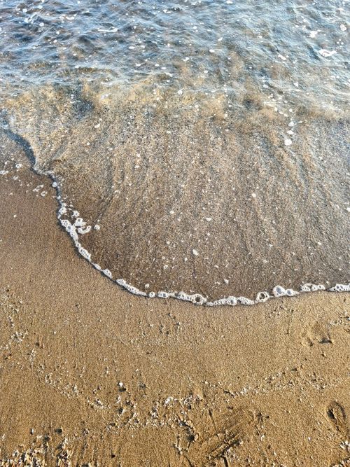 Free Peaceful seaside scene at Pozzuoli beach with gentle waves hitting the sand. Stock Photo