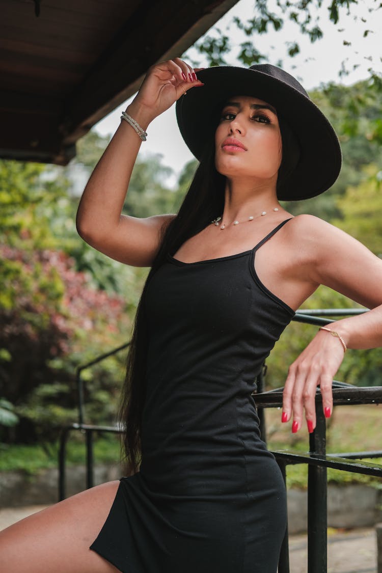 Woman Posing In A Black Dress And Hat 