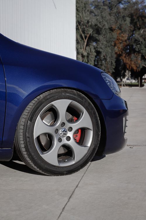 Free A close-up of a dark blue sports car, focusing on the front wheel, in an urban setting. Stock Photo