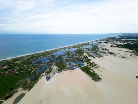 Drone captures expansive sand dunes and ocean in Fortaleza, Brazil, showcasing nature's beauty.