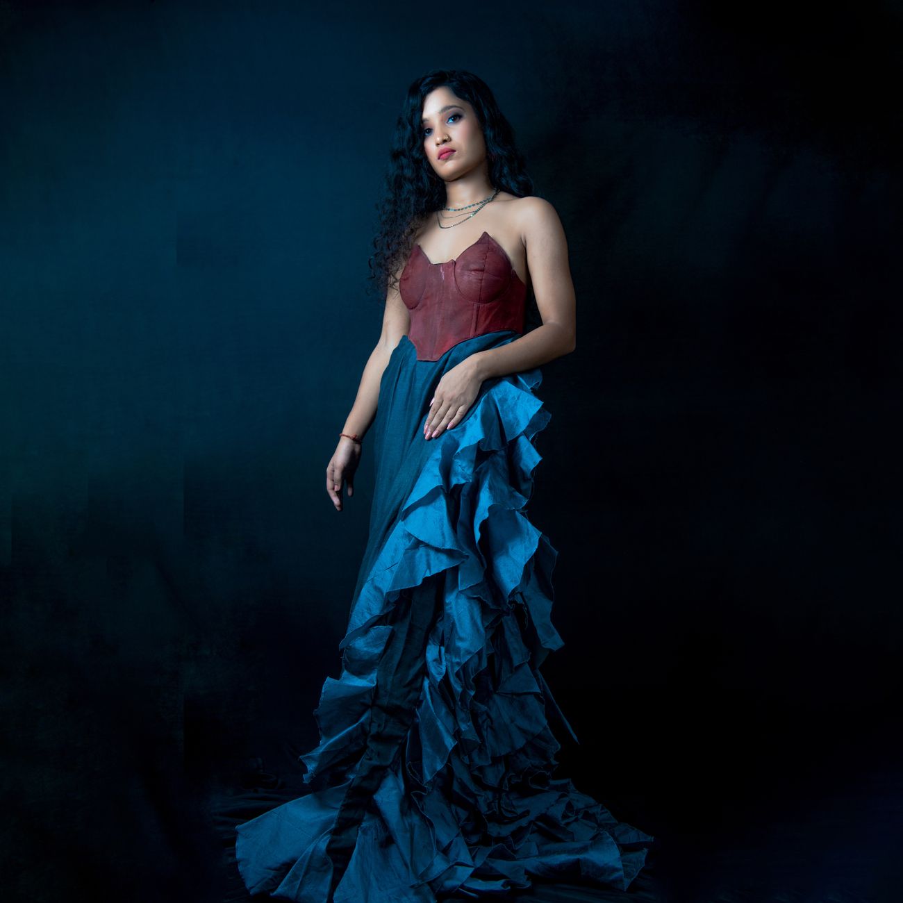 Artistic portrait showcasing a woman in a vibrant gown on a dark background.