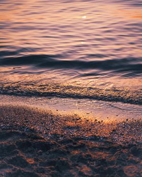 Pink-hued coastal waves gently lapping at the serene shores of Sunset Beach, ON, Canada.