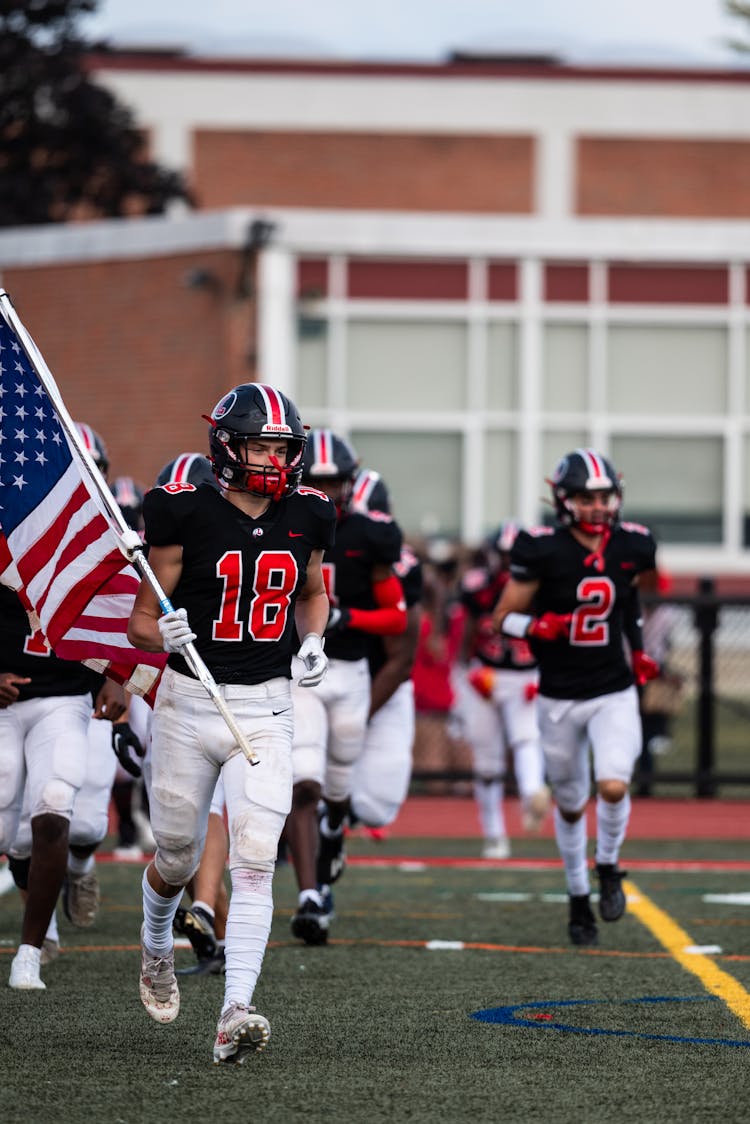 American Footballers Running With American Flag