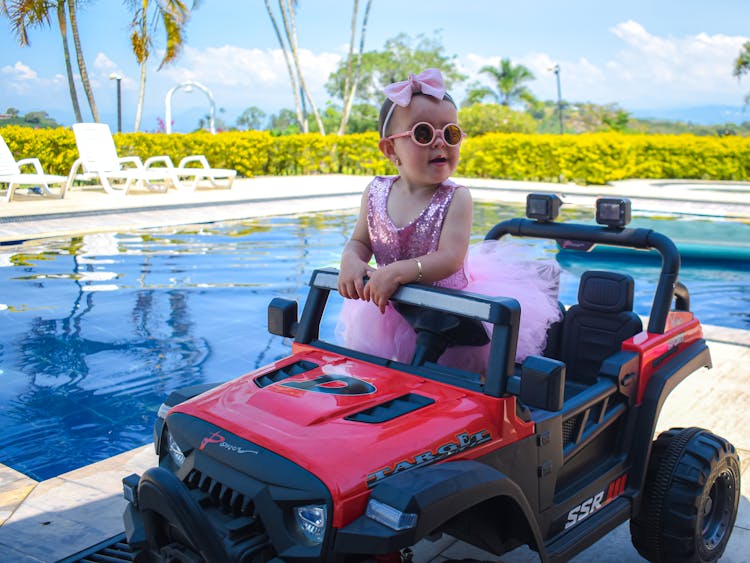 Happy Girl Sitting In A Toy Car