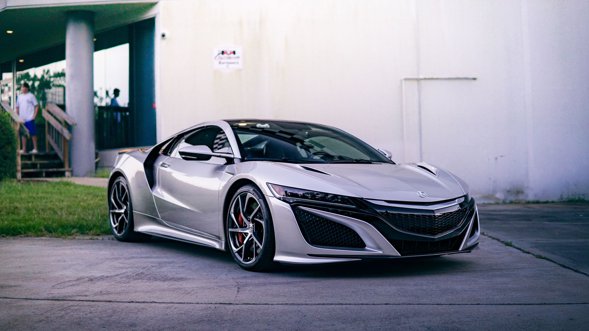 A stylish silver Acura NSX sports car parked in an urban environment, showcasing modern design and luxury.