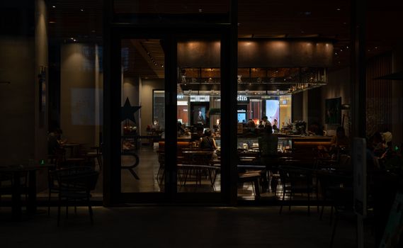 Warm and inviting nighttime interior view of a modern cafe with patrons enjoying the ambiance.
