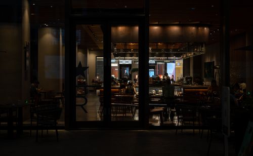 Free Warm and inviting nighttime interior view of a modern cafe with patrons enjoying the ambiance. Stock Photo