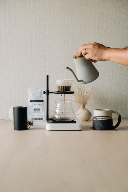 A hand pours water into a coffee filter using a kettle for pour-over brewing setup.