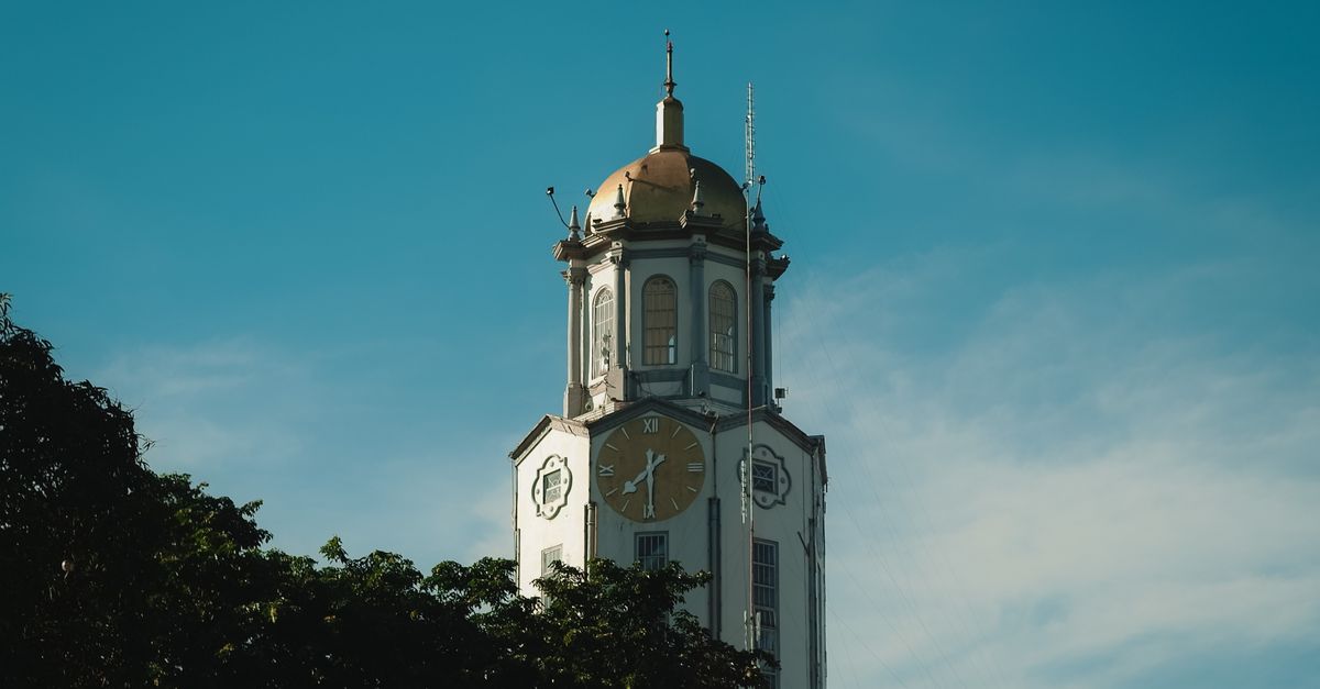Iconic clock tower in Manila, Philippines under a vibrant blue sky.