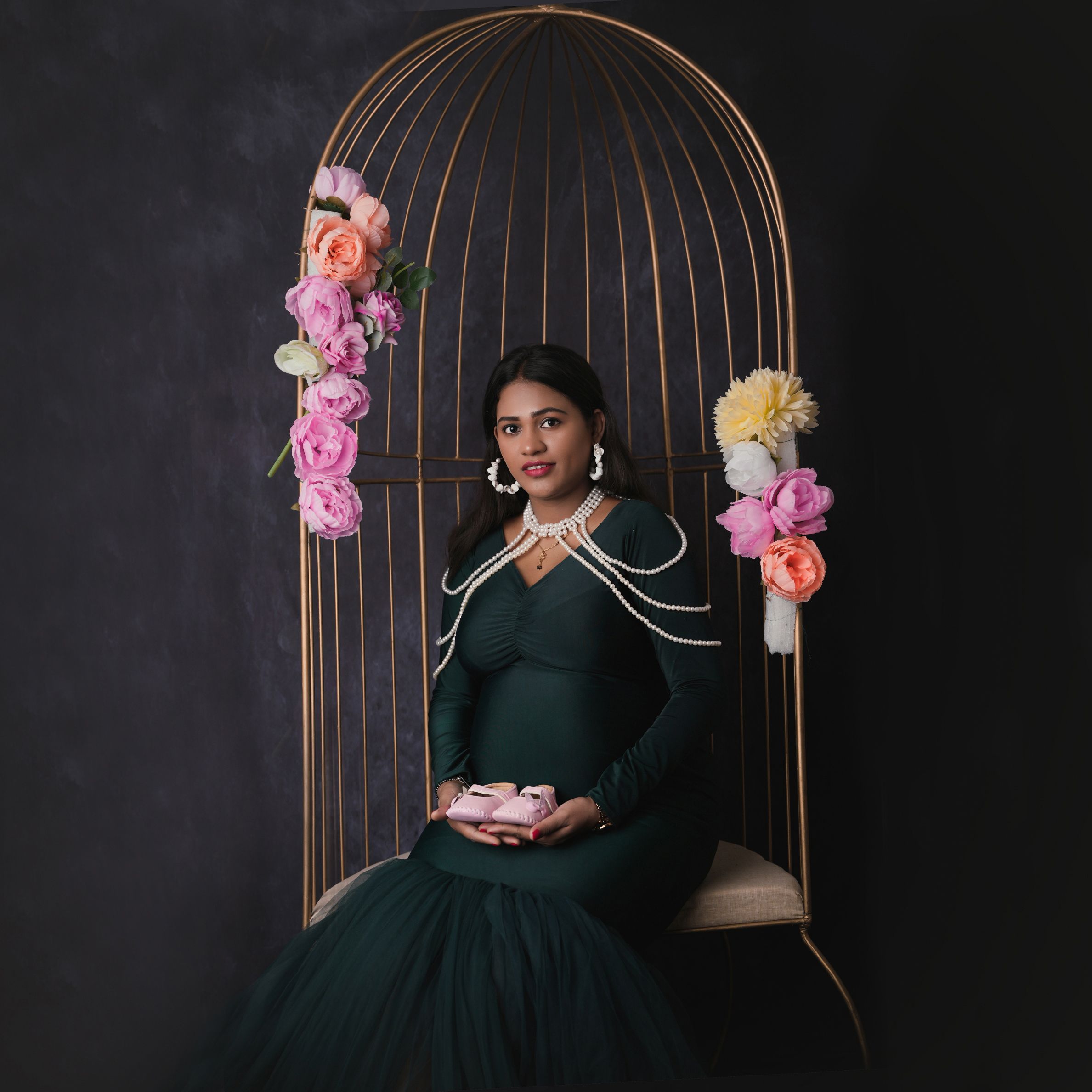 Pregnant Woman in Black Dress Sitting and Holding Baby Shoes  Free Stock  Photo