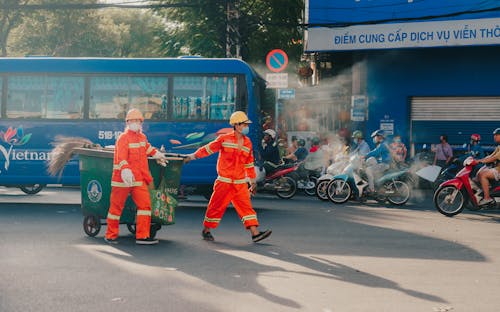 Workers Pulling a Garbage Bin on a Street in City 