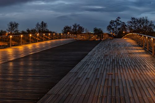 Free A serene evening view of a lit footbridge in Paris, showcasing ambient lights and a peaceful atmosphere. Stock Photo