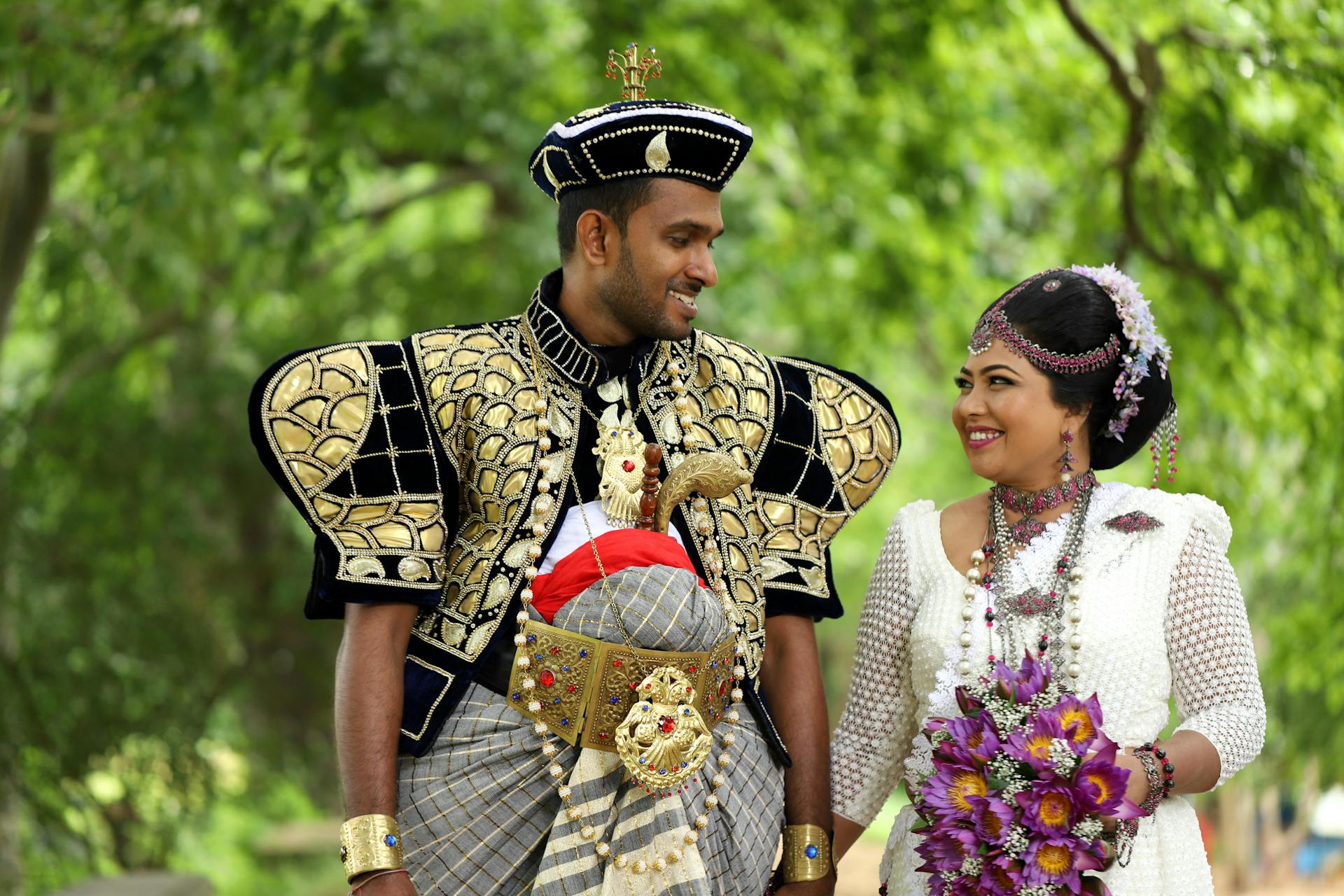 Celebrating a Sri Lankan couple in traditional wedding attire amidst a lush, green backdrop.