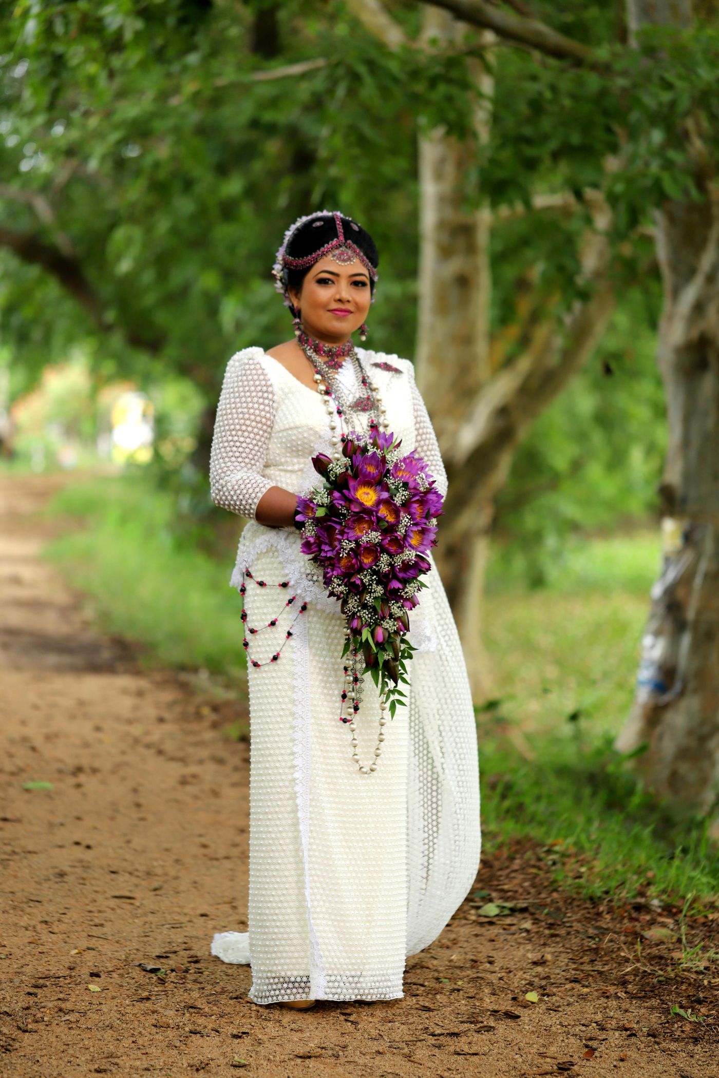 Kandyan bride in white osariya with cascading orchid bouquet