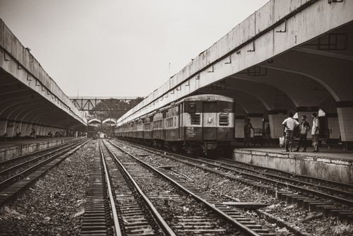 Free Black and white image of a train at a railway platform with people waiting. Stock Photo