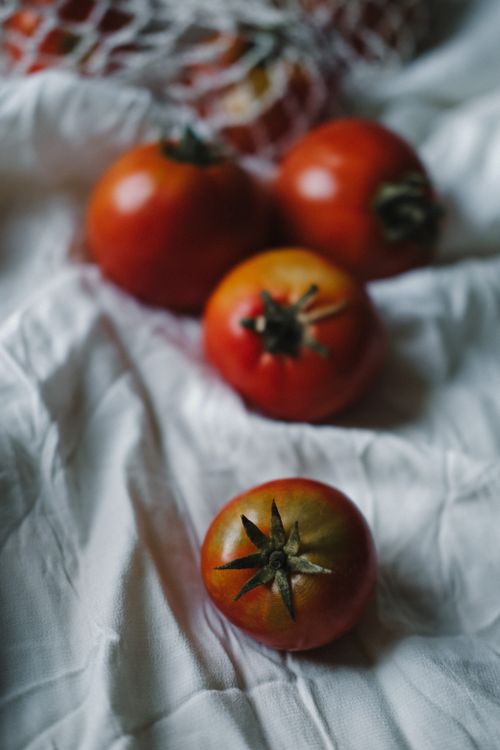 Free A close-up shot of ripe red tomatoes placed on a soft white cloth, showcasing food freshness. Stock Photo