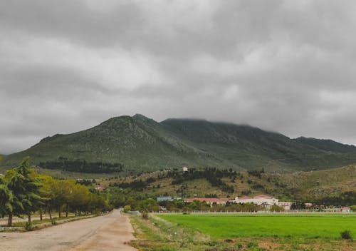 A Countryside Road and Mountains under a Cloudy Sky 
