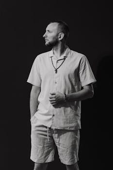 Black and white portrait of a confident man in casual summer attire, looking sideways.