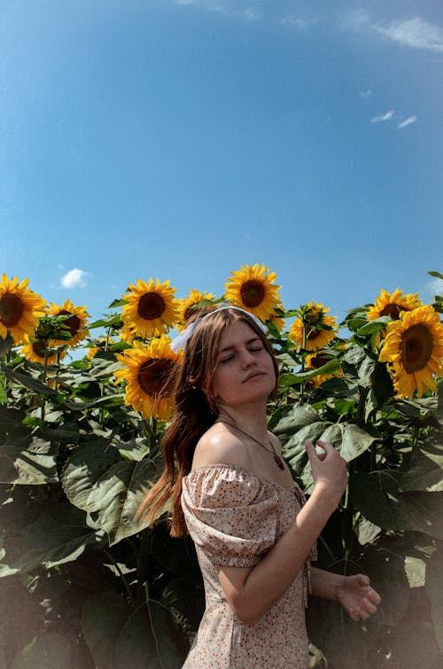 Woman in Sundress Standing with Sunflowers behind