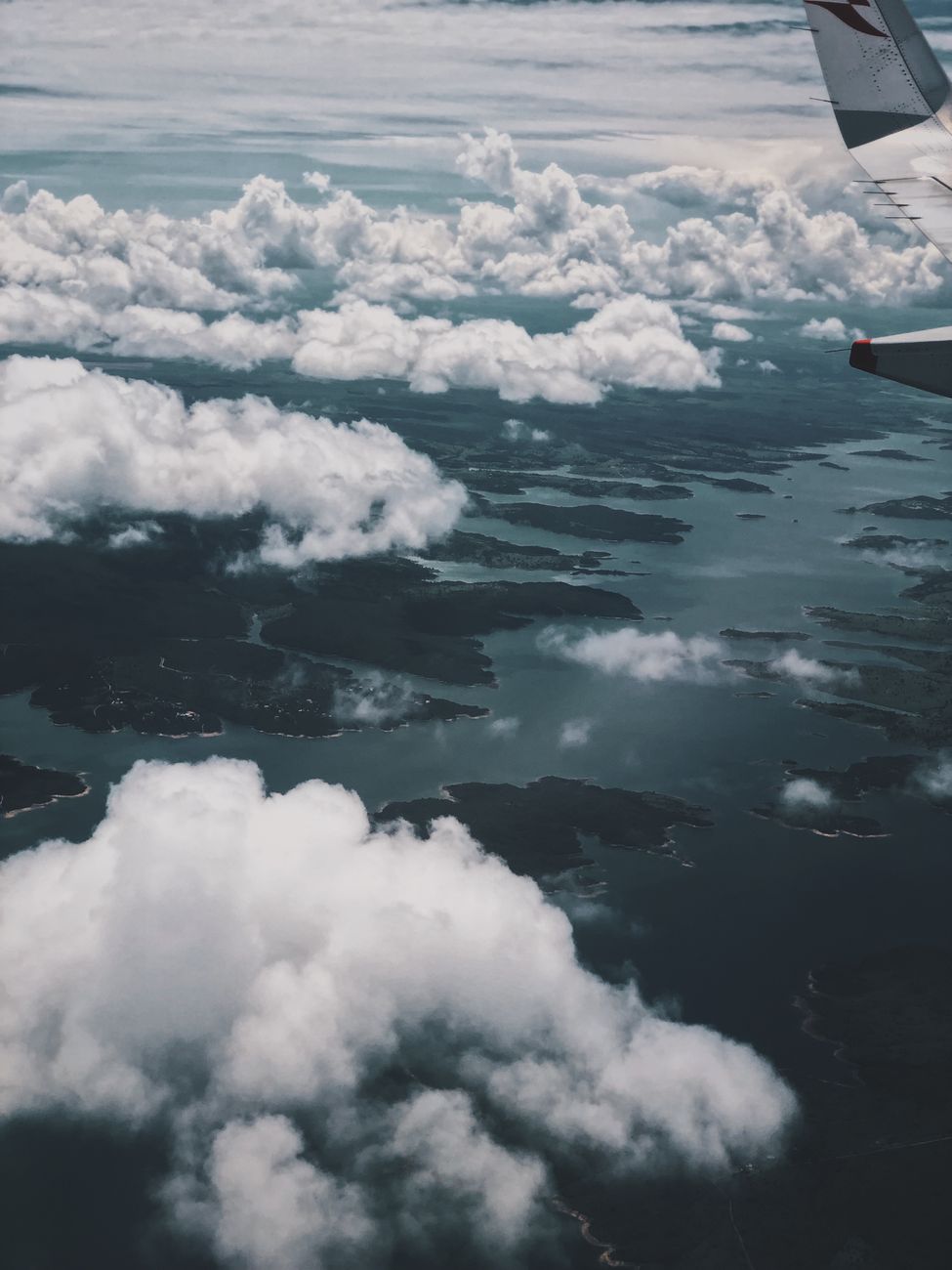 Stunning aerial view of island-dotted ocean with clouds from an airplane window.